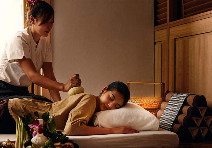 Người phụ nữ thư giãn trong buổi massage thảo dược tại spa sang trọng, trị liệu với tinh dầu, không gian ấm cúng.