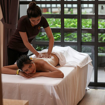 Nhân viên massage chuyên nghiệp thực hiện liệu pháp thư giãn tại spa cao cấp với khung cảnh thiên nhiên xanh mát.