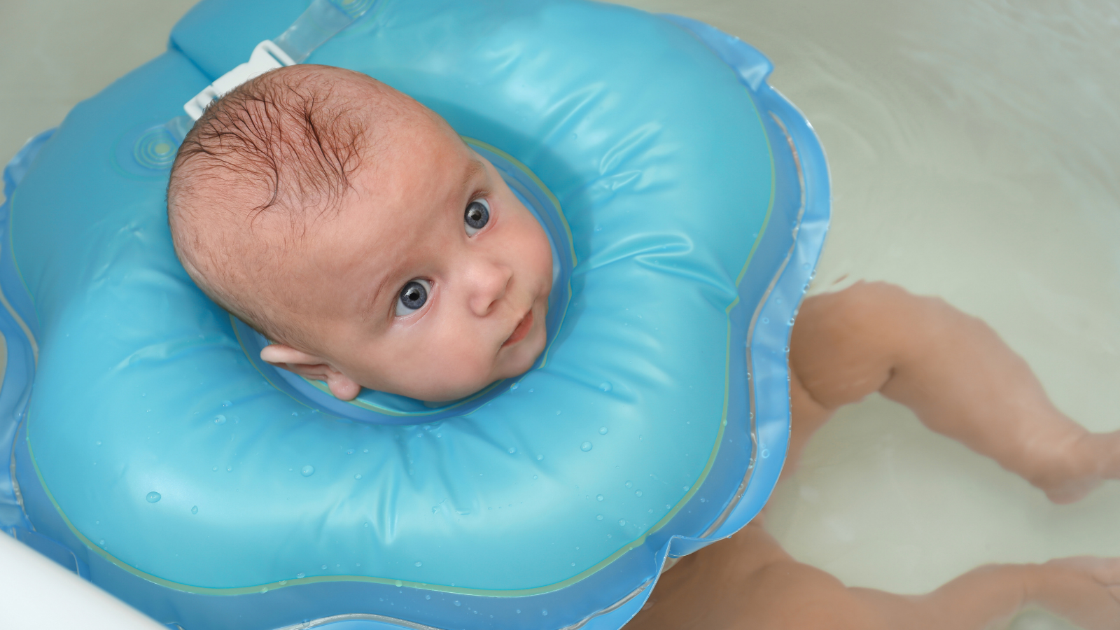 Lovely baby is swimming with float blue-collar in blue water.