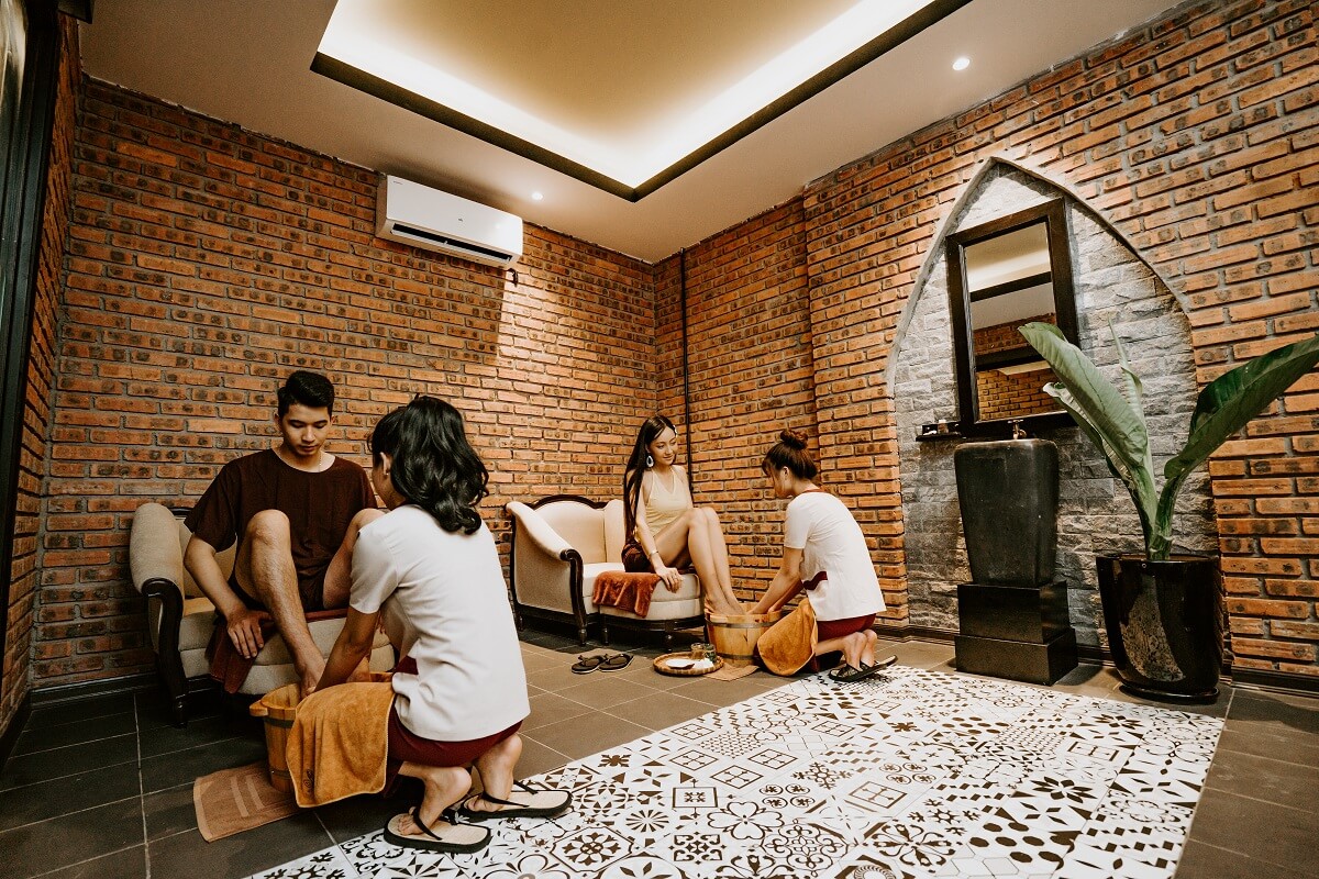 Khách hàng thư giãn tại spa với dịch vụ ngâm chân, không gian ấm cúng với tường gạch và cây xanh.