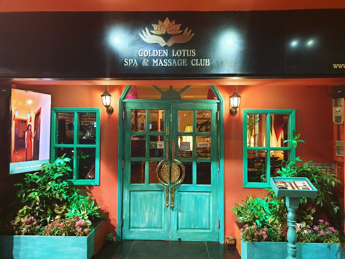 Mặt tiền Golden Lotus Spa & Massage Club với cửa màu xanh và cây xanh trang trí.