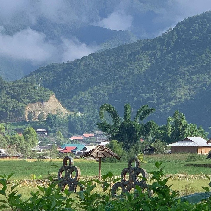 Thung lũng xanh mướt với cảnh núi non và ngôi làng nhỏ nhắn bên mây trời tại Tây Bắc Việt Nam.