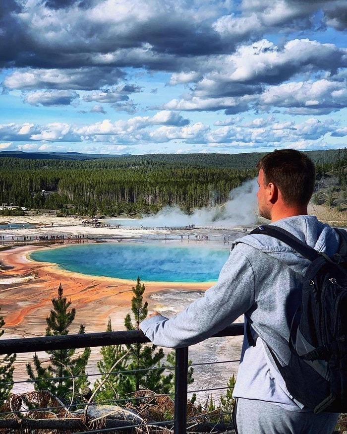 Người đàn ông đứng ngắm cảnh hồ nước xanh Grand Prismatic Spring ở công viên quốc gia Yellowstone.