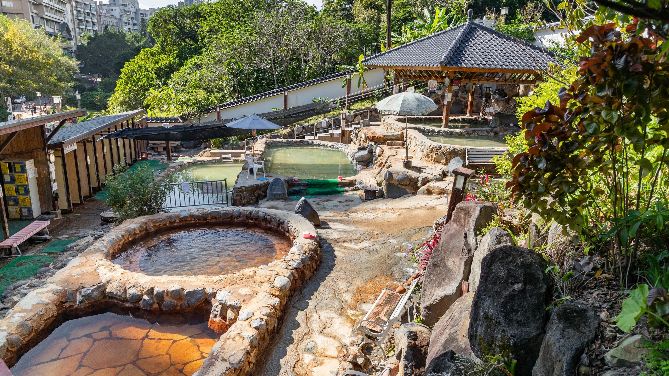 Khu nghỉ dưỡng onsen Nhật Bản với nhiều hồ nước nóng ngoài trời, cảnh quan xanh mát và kiến trúc truyền thống.