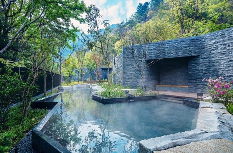 Khu nghỉ dưỡng spa ngoài trời với hồ nước nóng và cảnh quan thiên nhiên xanh mát ở môi trường núi.